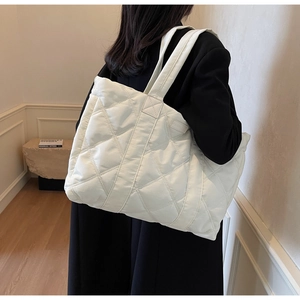 Dettaglio della grande borsa trapuntata bianca con etichetta Fashion su cappotto nero
