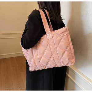 Vista dettagliata della borsa tote trapuntata rosa con cuciture a rombi e tracolla larga