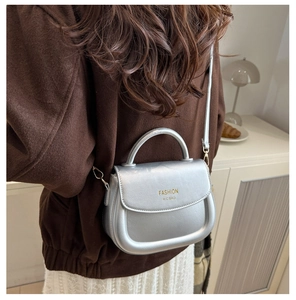Silver metallic saddle bag detail featuring golden lettering and stylish metal clasp