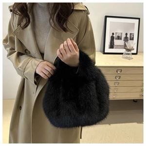 Detailed close-up of a soft black faux fur handbag featuring a plush round handle