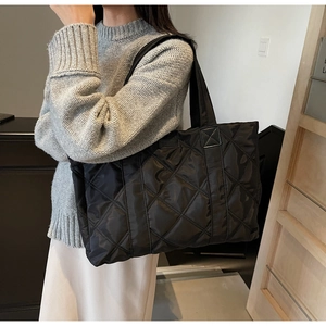 Dettaglio della borsa tote in nylon trapuntato con cuciture a diamante e tracolla nera