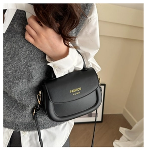 Close-up of black leather saddle bag with yellow FASHION H.C BAG text and gold hardware