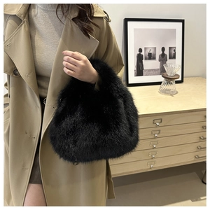 Close-up of fluffy black faux fur handbag held by a model wearing a khaki trench coat