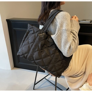 Dettaglio della borsa tote trapuntata nera con motivo a rombi ed etichetta Fashion