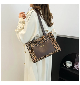 Detail of leopard print tote bag with brown leather pocket shown on model's shoulder