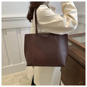 Detail of a large dark brown matte leather tote bag with silver bar and outer pocket