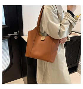 Detail of caramel brown matte leather tote bag with elegant buckle and seamless strap