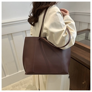Detail of dark brown tote bag with decorative stitching and long leather shoulder strap