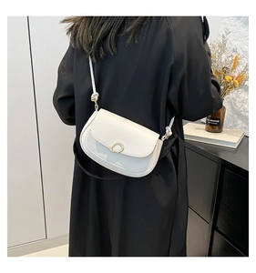 Elegant white saddle bag with gold buckle shown worn over a stylish black wool coat