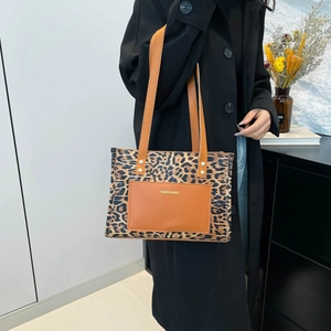 Elegante borsa tote leopardata con manici in pelle indossata da una modella in cappotto