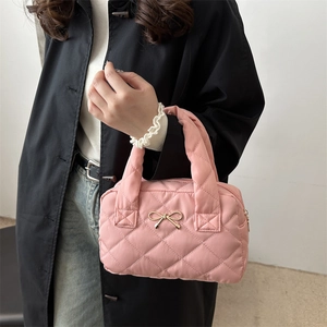 Pink quilted shoulder bag with gold bow detail worn by model in a casual outfit