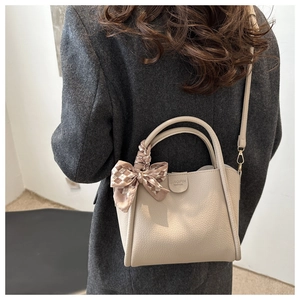 Détail du sac à main tendance avec texture cuir grainé et foulard en soie sur la poignée