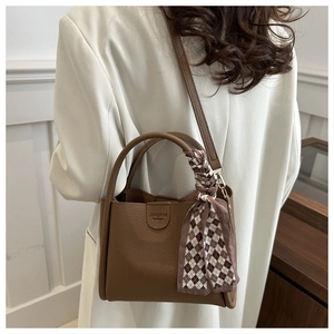 Gros plan du sac à main en cuir marron avec foulard décoratif et bandoulière amovible