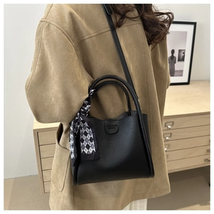 Détail du sac cabas en cuir grainé noir avec une décoration de foulard à carreaux chic