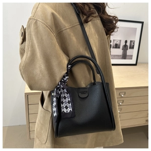 Détail du sac seau noir avec texture en cuir grainé et foulard décoratif à carreaux