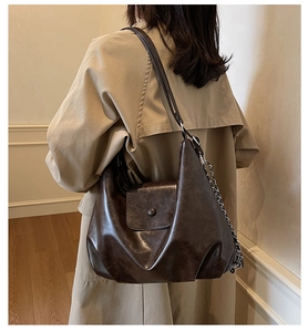 Detail of dark brown leather tote bag with vintage texture and silver chain strap