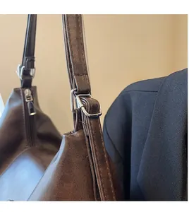 Close-up of adjustable long strap with silver buckle on brown vintage tote bag