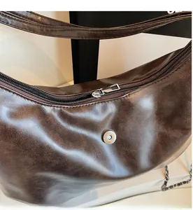 Detail of a dark brown hobo bag showing smooth zipper closure and magnetic snap button