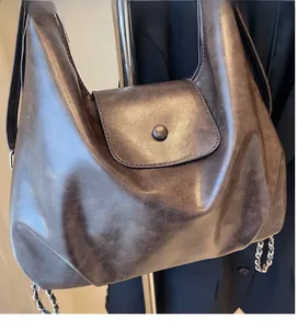 Detail of vintage brown leather tote bag showing soft texture and metal chain strap