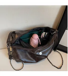 Detail of spacious brown leather tote interior with umbrella, notebook and bottle inside