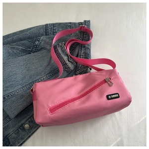 Détail d'un sac bandoulière en nylon rose avec fermeture éclair diagonale stylée