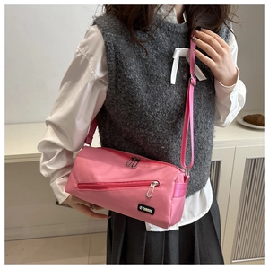 Détail du sac cylindrique en nylon rose avec écusson mode et poches zippées