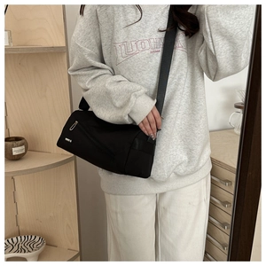 Détail du sac bandoulière en nylon noir imperméable avec poche zippée et bandoulière
