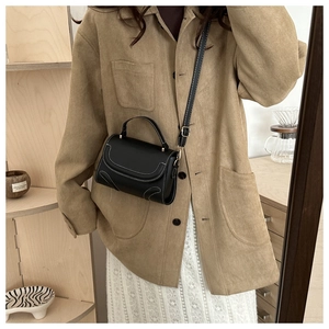 Detail einer minimalistischen schwarzen Umhängetasche mit Kontrastnähten an einem Model