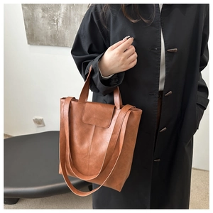 Close-up of brown PU leather tote bag with FASHION & BAGS logo held by a model