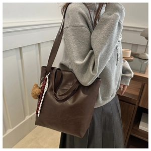 Detail of dark brown tote bag with bear charm and Fashion & Bag embossed logo
