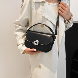 Chic black faux leather handbag with silver heart buckle for women on white trench coat