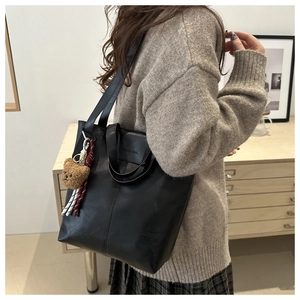 Detail of black PU tote bag with shoulder straps, plush bear charm and silk scarf