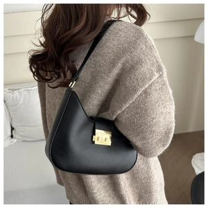 Detailed close-up of a black leather crescent hobo bag with a gold metal clasp on a model