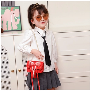 Bambina con borsa in tweed rosso con grande fiocco e raffinato manico di perle
