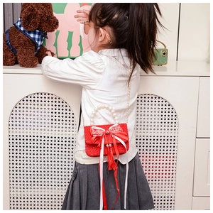 Dettaglio mini borsa rossa in tweed per bambina con manico di perle e nappine a nastro