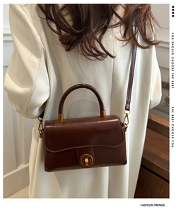 Détail du sac vintage en cuir ciré marron foncé avec boucle rotative ronde dorée