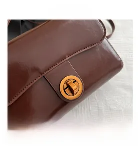 Détail du sac à main en cuir marron foncé avec fermoir rotatif en métal bronze vintage