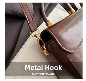 Détail d'un sac à main marron brillant avec crochets en métal doré et bandoulière