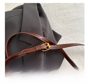 Détail de la boucle dorée réglable et de la bandoulière en cuir marron d'un sac à main