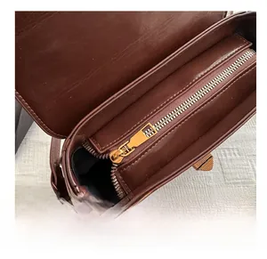 Gros plan sur la fermeture éclair dorée et le compartiment interne du sac en cuir marron