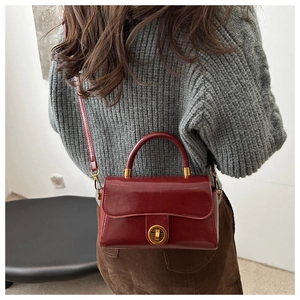 Détail d'un sac à main en cuir bordeaux avec fermoir tournant doré et poignée chic