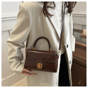 Détail du sac à main en cuir verni marron foncé avec fermoir rotatif doré et anse