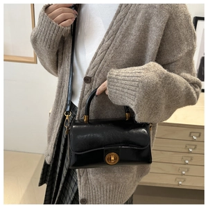 Détail d'un sac à main en cuir verni noir brillant avec un fermoir doré rotatif chic