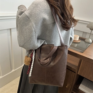 Minimalist dark brown leather tote bag with plush bear charm for autumn 2025 fashion