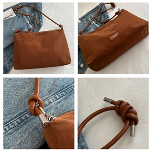 Detail view of brown matte shoulder bag featuring knotted straps and silver metal hardware