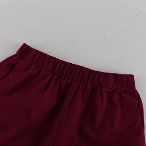 Detail eines weinroten breiten elastischen Bundes mit Plisseetextur und Seitentaschen