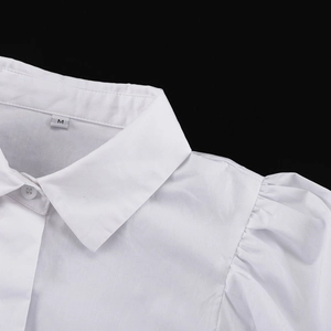 Dettaglio camicia in cotone bianco con manica a sbuffo ed etichetta taglia M