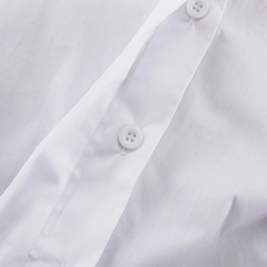 Dettaglio del tessuto in cotone bianco e del bottone rotondo a quattro fori della camicia