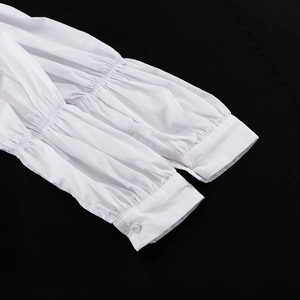 Dettaglio della camicia in cotone bianco con polsini a sbuffo pieghettati e bottone