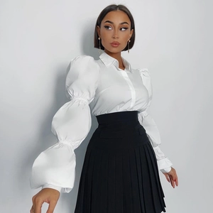 Camicia da donna in cotone bianco con maniche a sbuffo e gonna a pieghe nera a vita alta